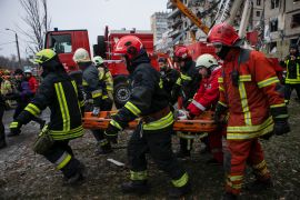 Emergency workers carry a wounded woman after a Russian rocket hit a multistory building on Saturday in Dnipro, Ukraine, Sunday, Jan. 15, 2023. (AP Photo/Yevhenii Zavhorodnii)