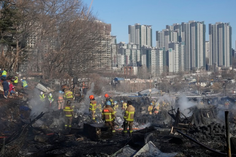 A view of Guryong after the fire was extinguished. Smoke is rising the ash and there are skyscrapers behind