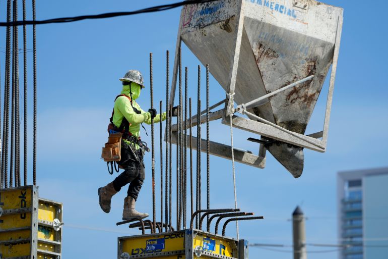 A worker guides a bin into position at a construction site, Tuesday, in Miami, Florida, US