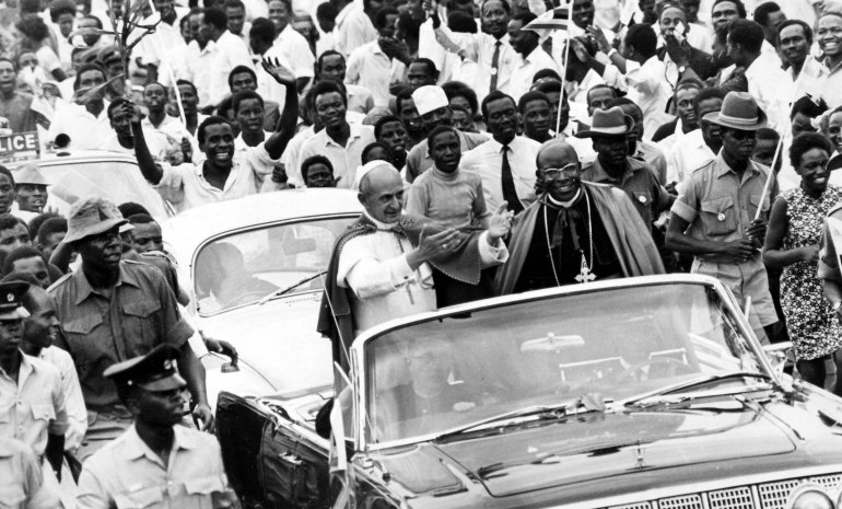 FILE - In this July 31, 1969 file photo, Pope Paul VI standing in an open car waves to the crowd jamming the road to welcome him to Africa, accompanied by Archbishop of Kampala Emmanuel Kiwanuka Nsubuga, right, in Kampala, Uganda. Pope Francis follows his predecessors next week Nov. 25-30, 2015 to visit Africa whose growing numbers of Catholics are seen as a bulwark for a church seeking to broaden its appeal amid secularism, competing Christian faiths and violent extremism, in a trip that will take him to Kenya, Uganda and the Central African Republic. (AP Photo, File)