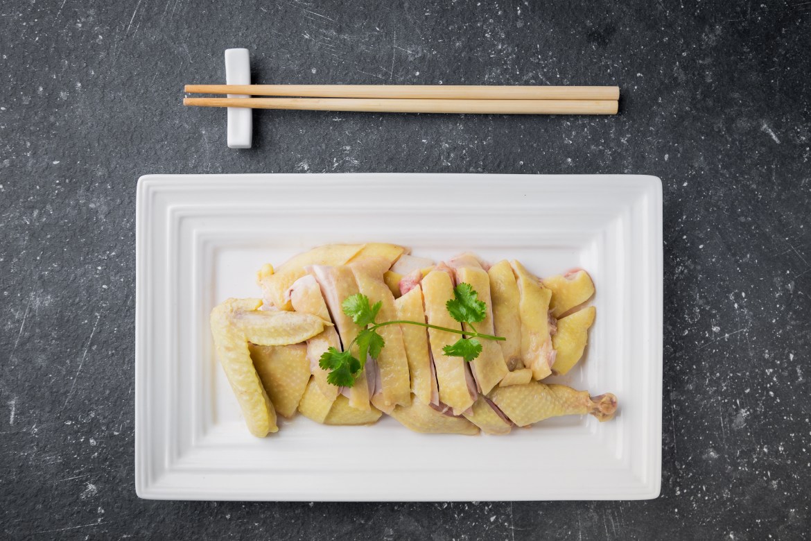 a plate of steamed chicken with chopsticks laying across the top