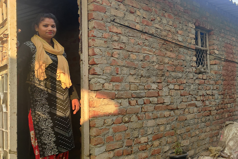 A photo of Gunja standing at the entrance of her new house.