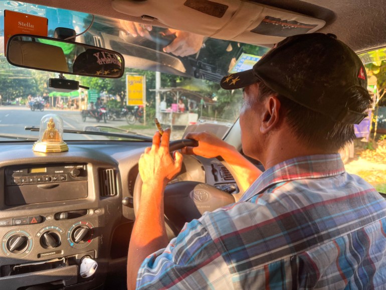 A photo of Lu Zaw driving his cab while holding a cigarette.
