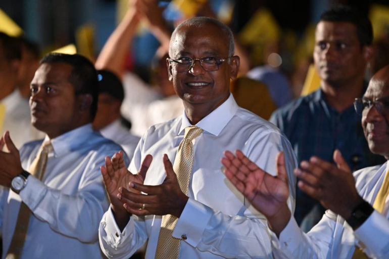 Maldives President Ibrahim Mohamed Solih at a campaign event in Addu, Maldives. He is wearing a shirt and tie and clapping. People around him are clapping as well.