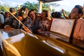 Family members of slain Honduran environmentalists Aly Dominguez and Jairo Bonilla mourn over their caskets [Seth Berry/Al Jazeera]