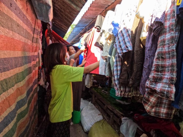 A photo of people shopping for second hand clothes at a market.