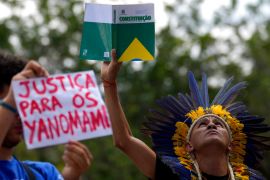 An Indigenous leader raises a copy of Brazil's constitution at a protest.