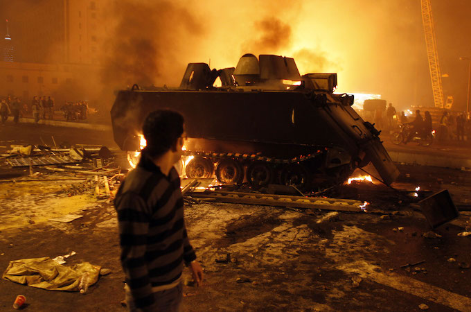 A protester looks at a burned Egyptian Army armoured vehicle in downtown Cairo on January 28. GORAN TOMASEVIC/REUTERS