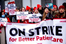 A picket line of nurses hold a sign reading 'on strike'