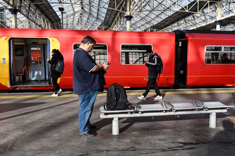 Commuters walk past a train stopped at a platform in Waterloo Station in London,