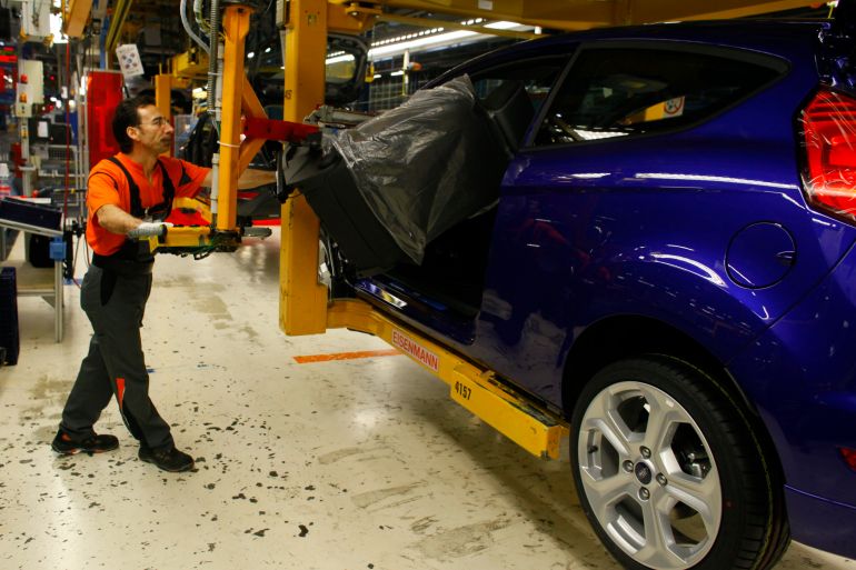 A worker mounts a seat inside a Fiesta ST at the Fiesta assembly line of Ford Germany in Cologne