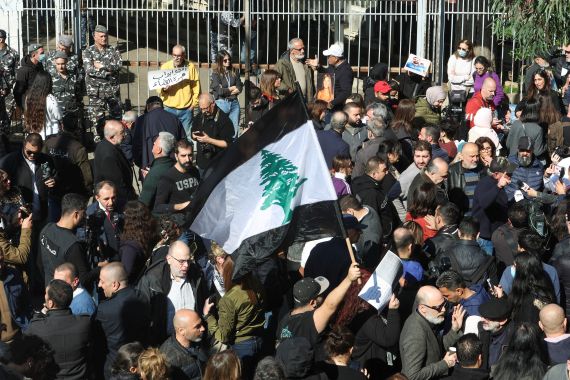 A demonstrator holds a black and white Lebanese flag during a protest for Families of the victims of the 2020 Beirut port explosion against Lebanon's top public prosecutor who charged the judge investigating the Beirut port blast and ordered the release of those detained in connection with the explosion in front of the Justice Palace in Beirut, Lebanon January 26, 2023.
