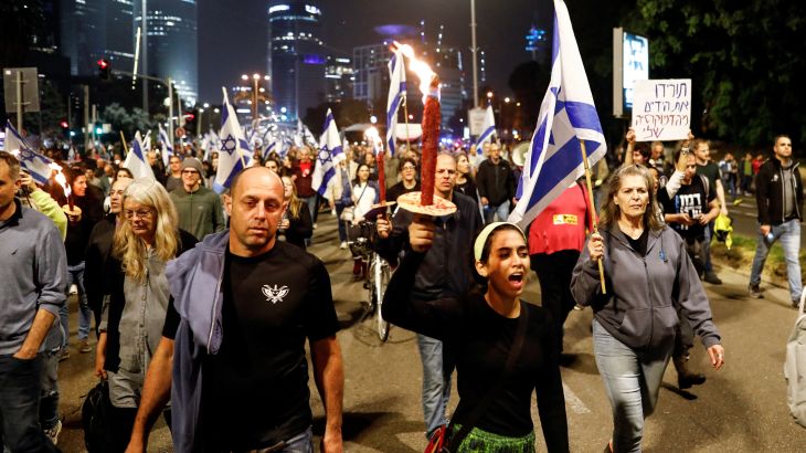 A protestor holds a torch during a demonstration against proposed judicial reforms by Israel's new right-wing government, in Tel Aviv