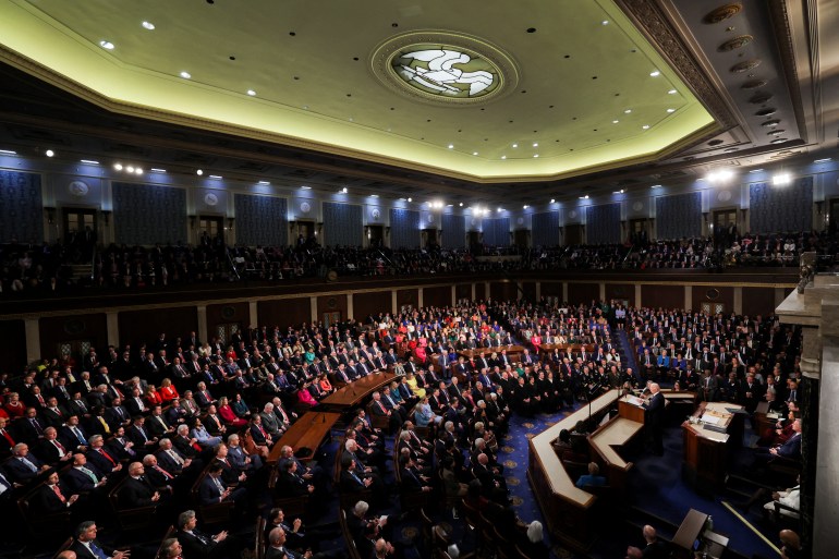 Biden addresses House of Representatives from the top left hand side. The chamber is full and view shows green ceiling with the white eagle artwork.