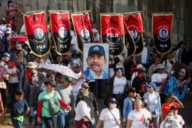 Supporters of Daniel Ortega march with the red and black banners of the Sandanista National Liberation Front and a portrait of Ortega