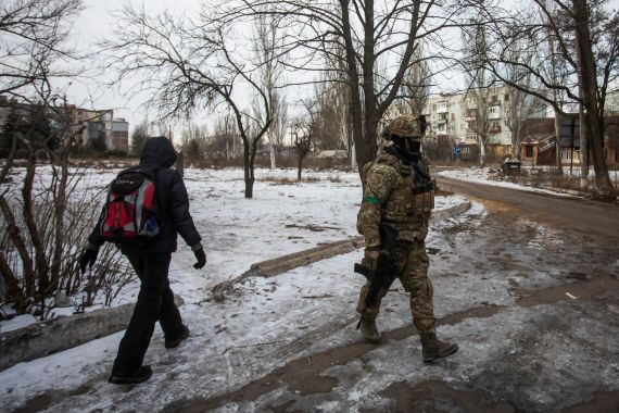 A resident walks past a Ukrainian service member on a street, in the front line town of Bakhmut, Ukraine.