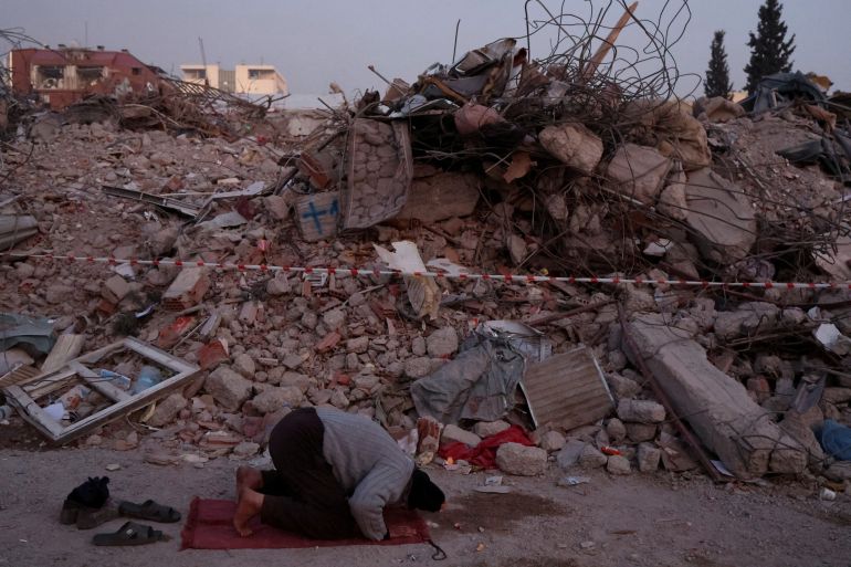 A man prays near the rubble of destroyed homes, in the aftermath of a deadly earthquake in Kahramanmaras, Turkey