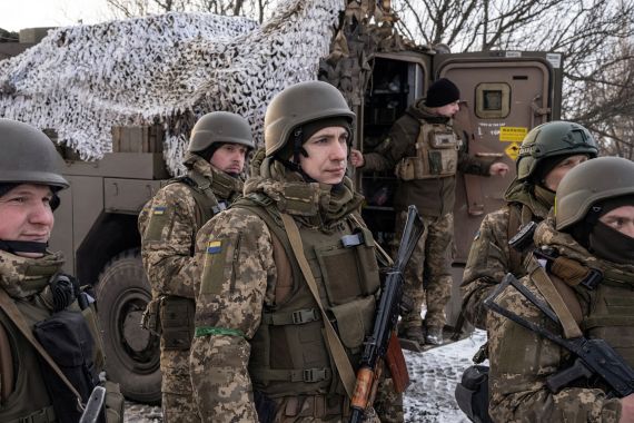 Ukrainian servicemen of the 80th Air Assault Brigade stand in front of a Bushmaster Protected Mobility Vehicle