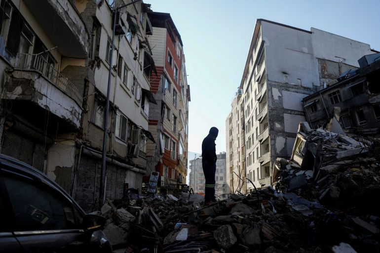A man stands on rubble, in the aftermath of the deadly earthquake, in Antakya, Turkey February 17, 2023.