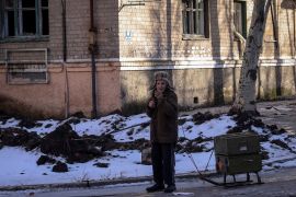 A resident rests as he walks with empty ammunition boxes on a street in the front-line city of Bakhmut, Ukraine.