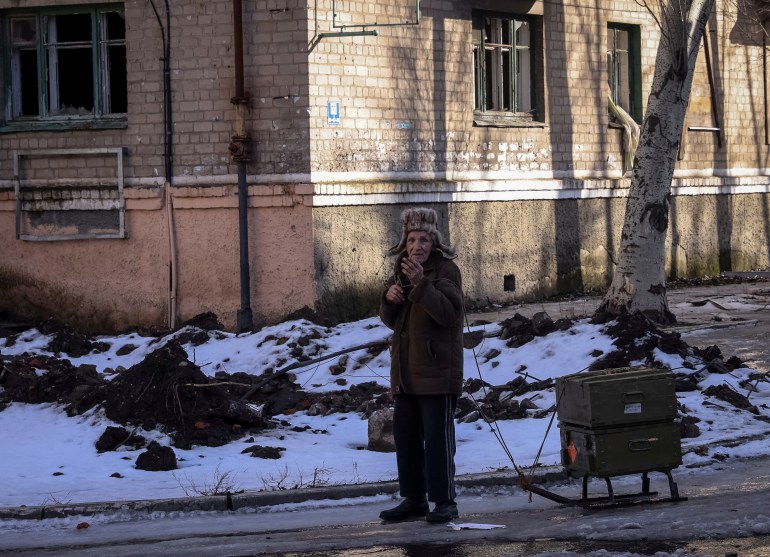A local resident rests as he walks with empty ammunition boxes on a street, as Russia's attack on Ukraine continues, in the front line city of Bakhmut, Ukraine February 19, 2023. REUTERS/Yevhen Titov TPX IMAGES OF THE DAY