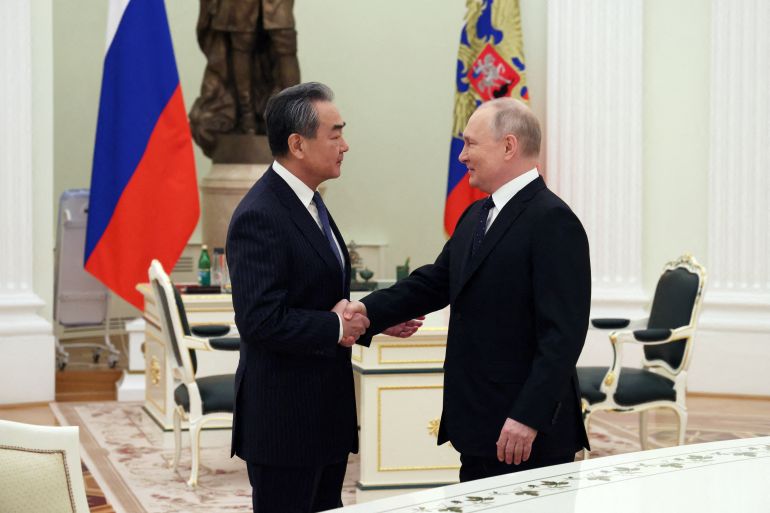 Russian President Vladimir Putin shakes hands with China's top diplomat Wang Yi during a meeting in Moscow, Russia on February 22, 2023 [Sputnik/Anton Novoderezhkin/pool via Reuters]