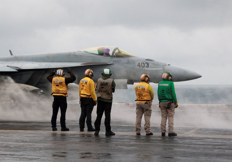 FILE PHOTO: Crew members signal to a F/A-18E Super Hornet fighter jet preparing to take off for a routine flight on board the U.S. USS Nimitz aircraft carrier during a routine deployment to the South China Sea, Mid-Sea, January 27, 2023. REUTERS/Joseph Campbell//File Photo