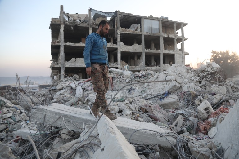 A man walks over the rubble of his home