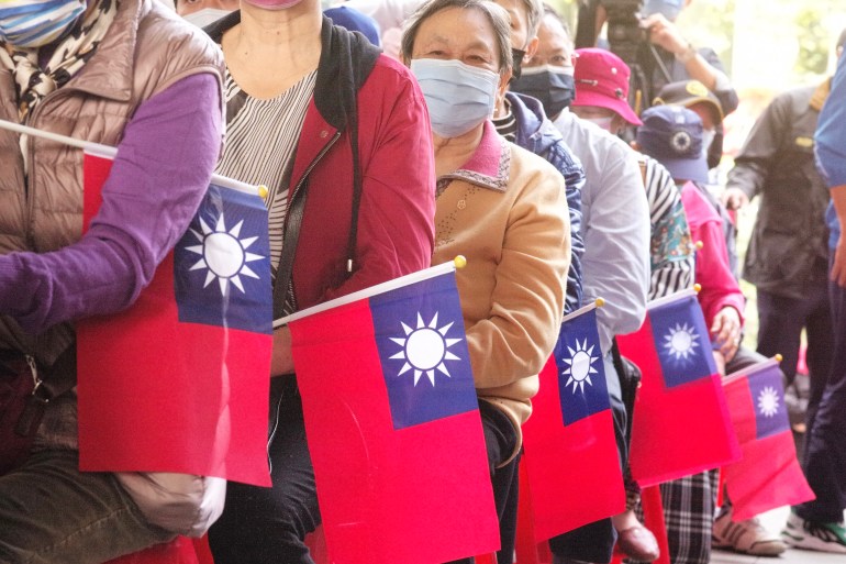 KMT supporters standing in a line holding small Taiwan flags.