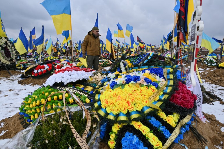 A man walks among graves of Ukrainian soldiers in the "Alley of Glory" of a cemetery in Kharkiv, Ukraine.