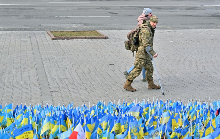 A wounded Ukrainian serviceman and his girlfriend walk past national flags
