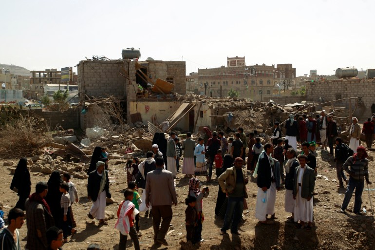 Yemenis walk past the ruins of buildings destroyed in an air-strike by the Saudi-led coalition
