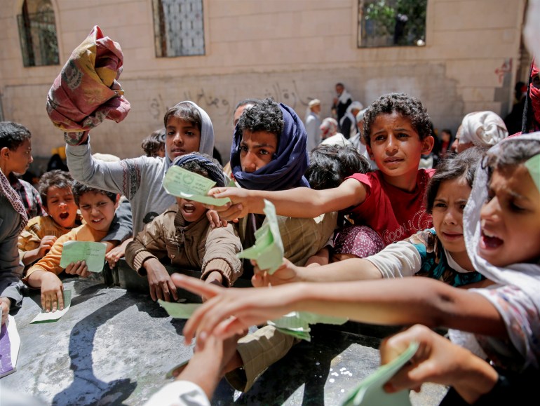 Yemenis present documents in order to receive food rations provided by a local charity, in Sanaa