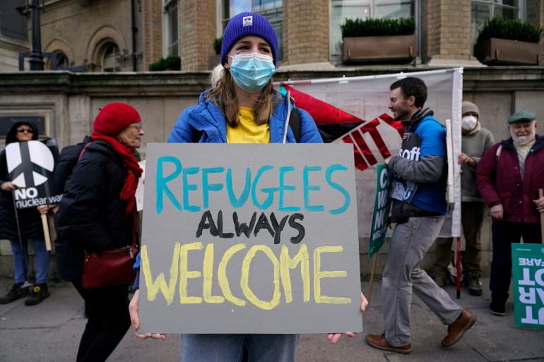 A demonstrator holds a placard saying 'Refugees always welcome' during an anti-war march, in London