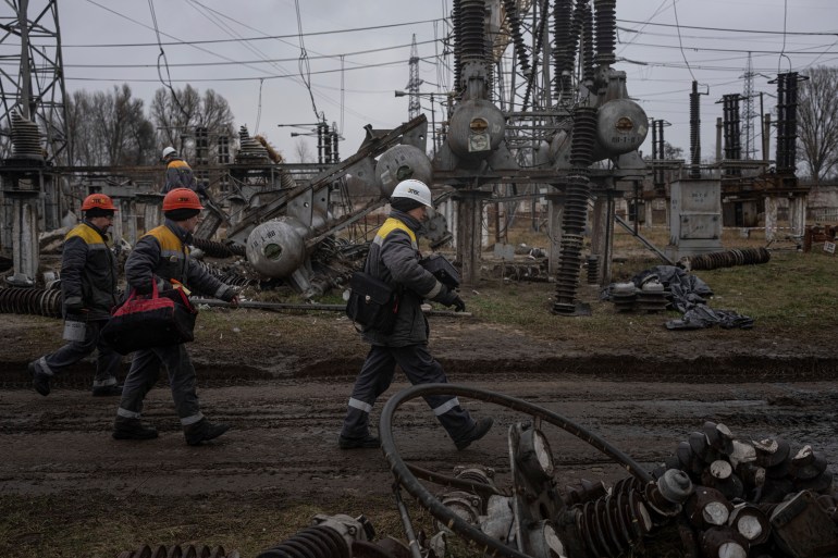 Power plant workers walk to repair damages after a Russian attack in central Ukraine