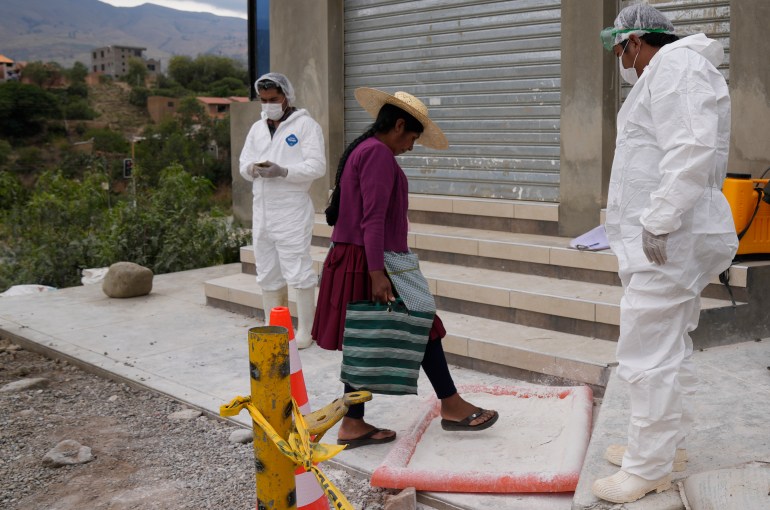 A woman steps on lime, set up by health workers who created a sanatation perimeter near chicken farms, as she walks home amid a health alert due to a bird flu outbreak in Sacaba, Bolivia.