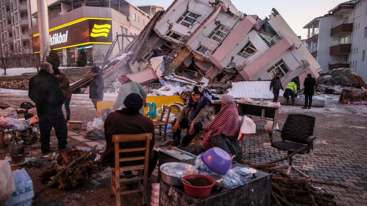 People stand by collapsed buildings in Golbasi, in Adiyaman province, southern Turkey