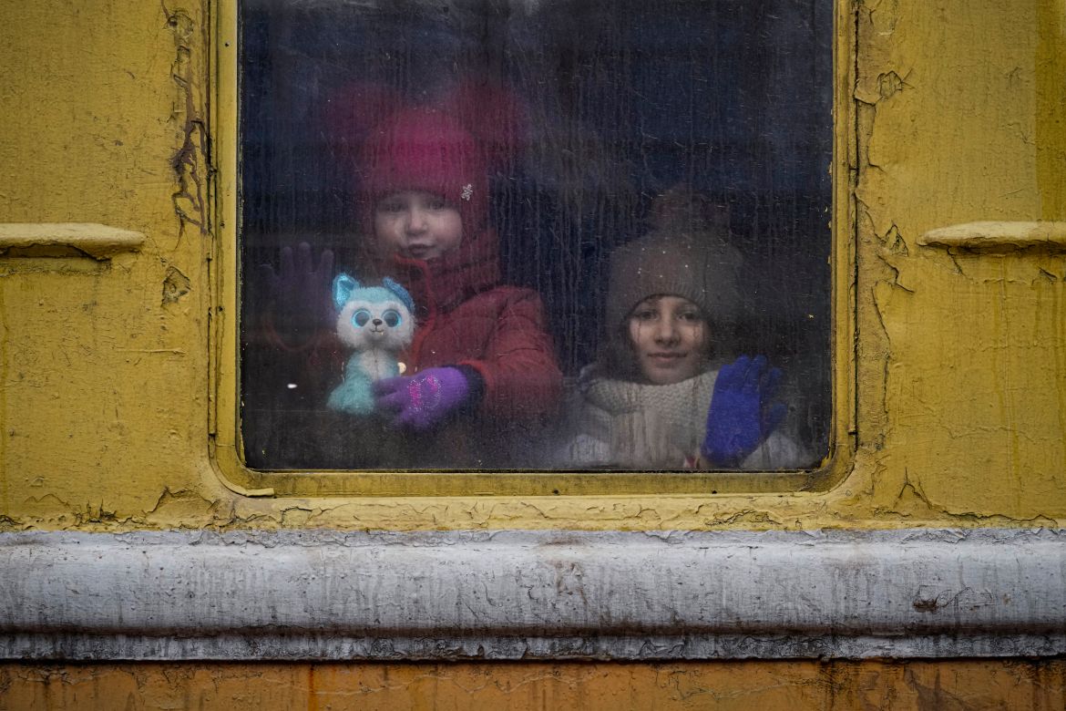 Children look out of the window of an unheated Lviv-bound train, in Kyiv
