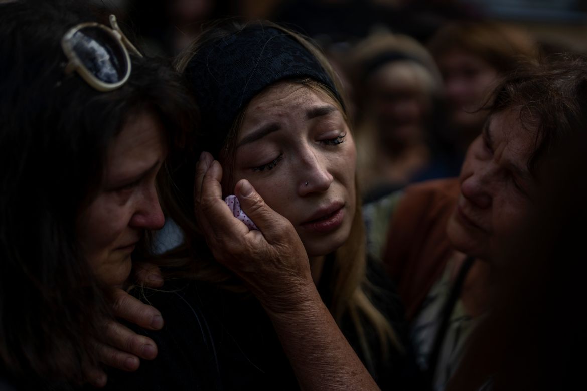 Anastasia Ohrimenko, 26, is comforted by relatives as she cries next to the coffin of her husband