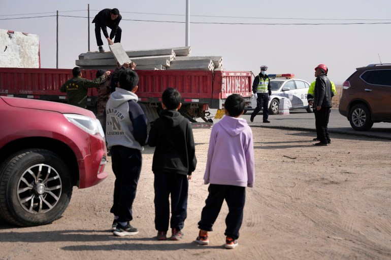 People gather at a checkpoint along a road leading to the site of a collapsed mine in China
