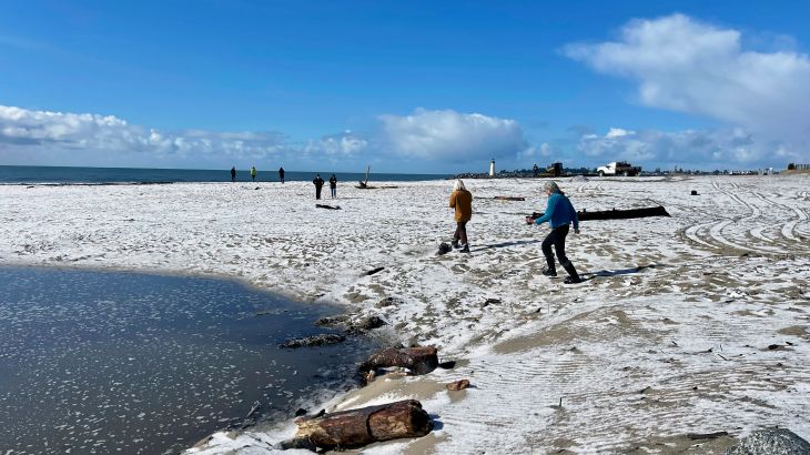 People walk along a snow-covered beach in Santa Cruz, California