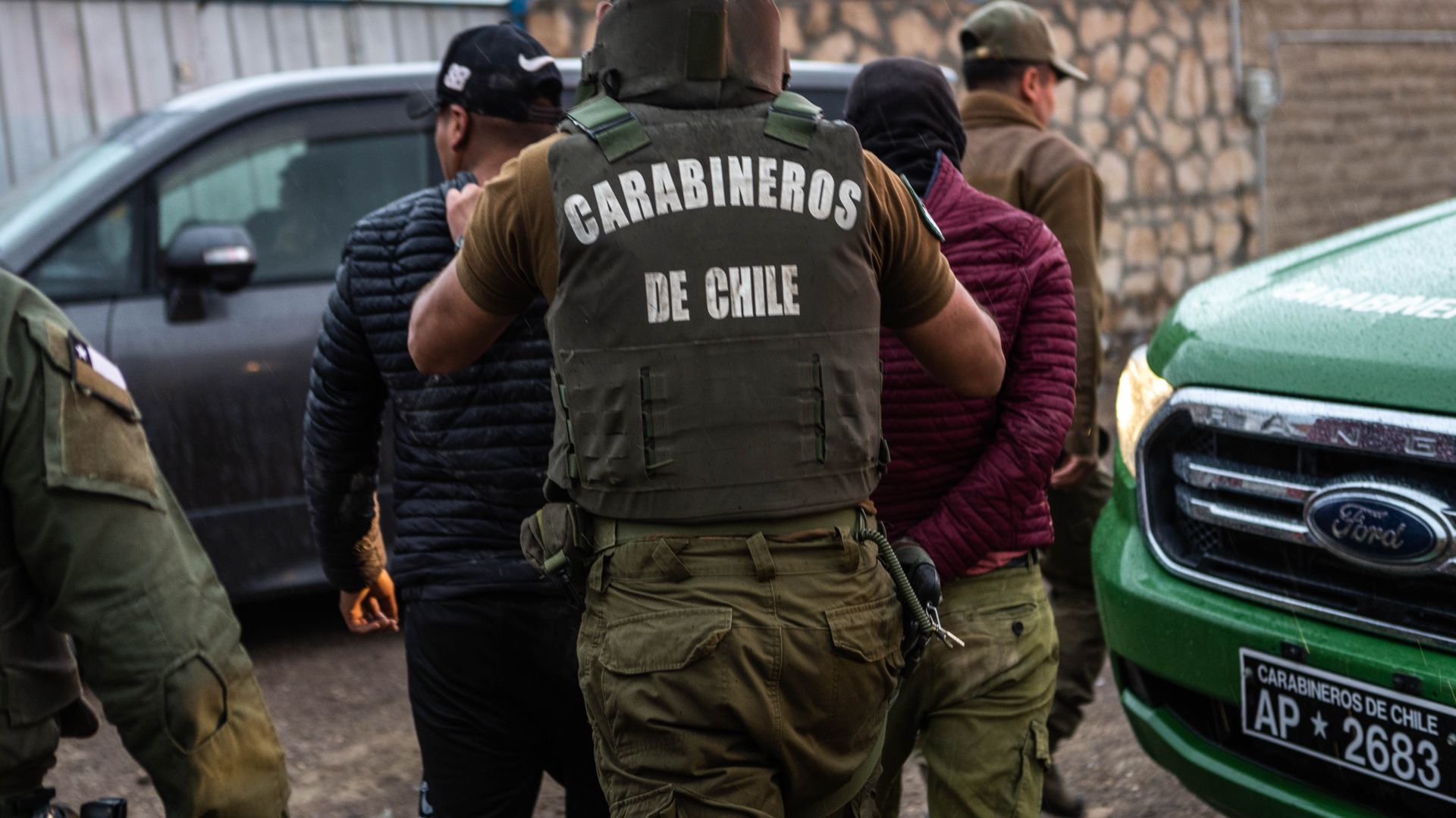 Law enforcement — wearing flak vests labelled "Carabineros de Chile" — make arrests along the border.