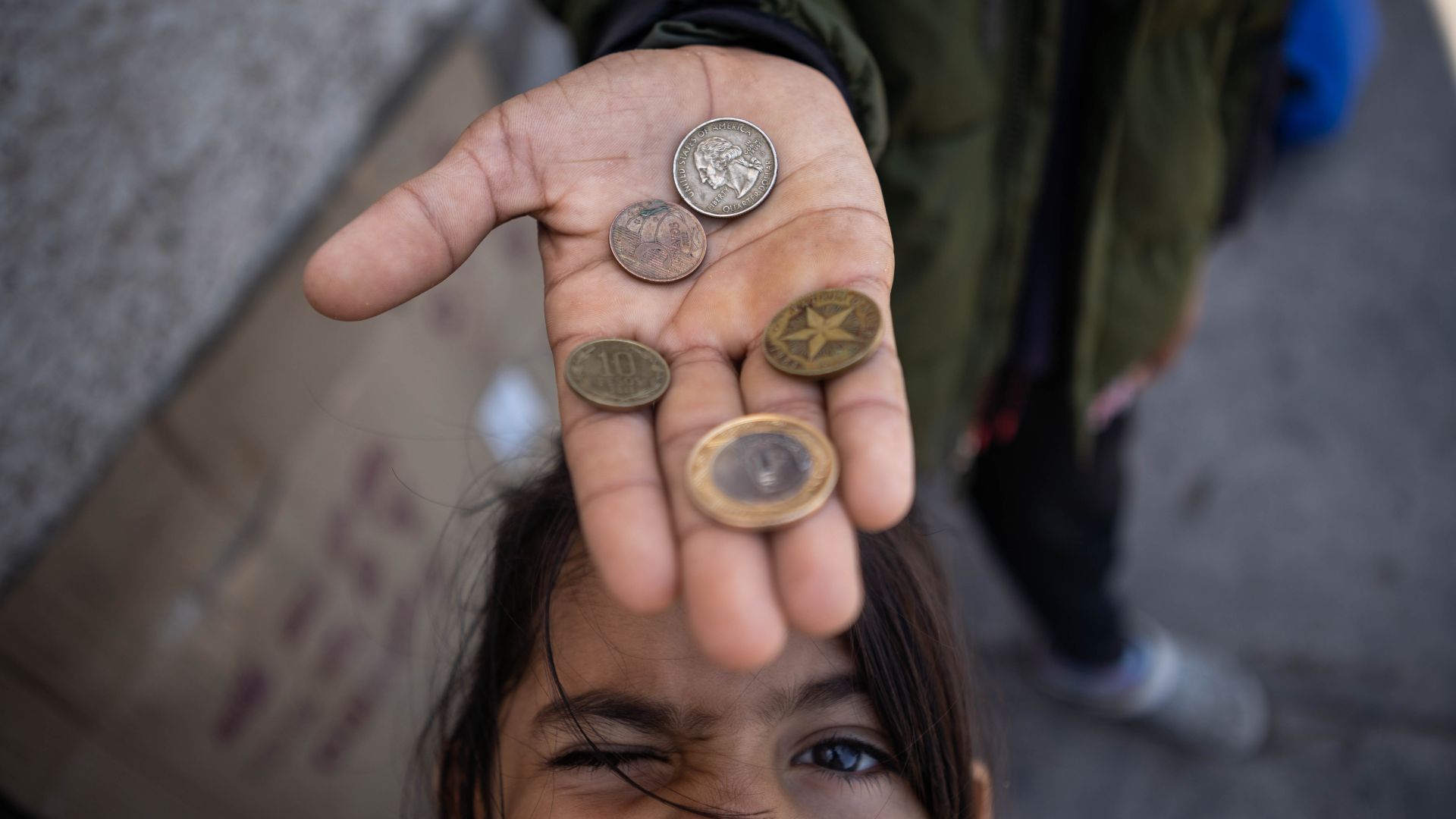 Five-year-old Allyson poses beneath an outstretched hand holding a few coins.