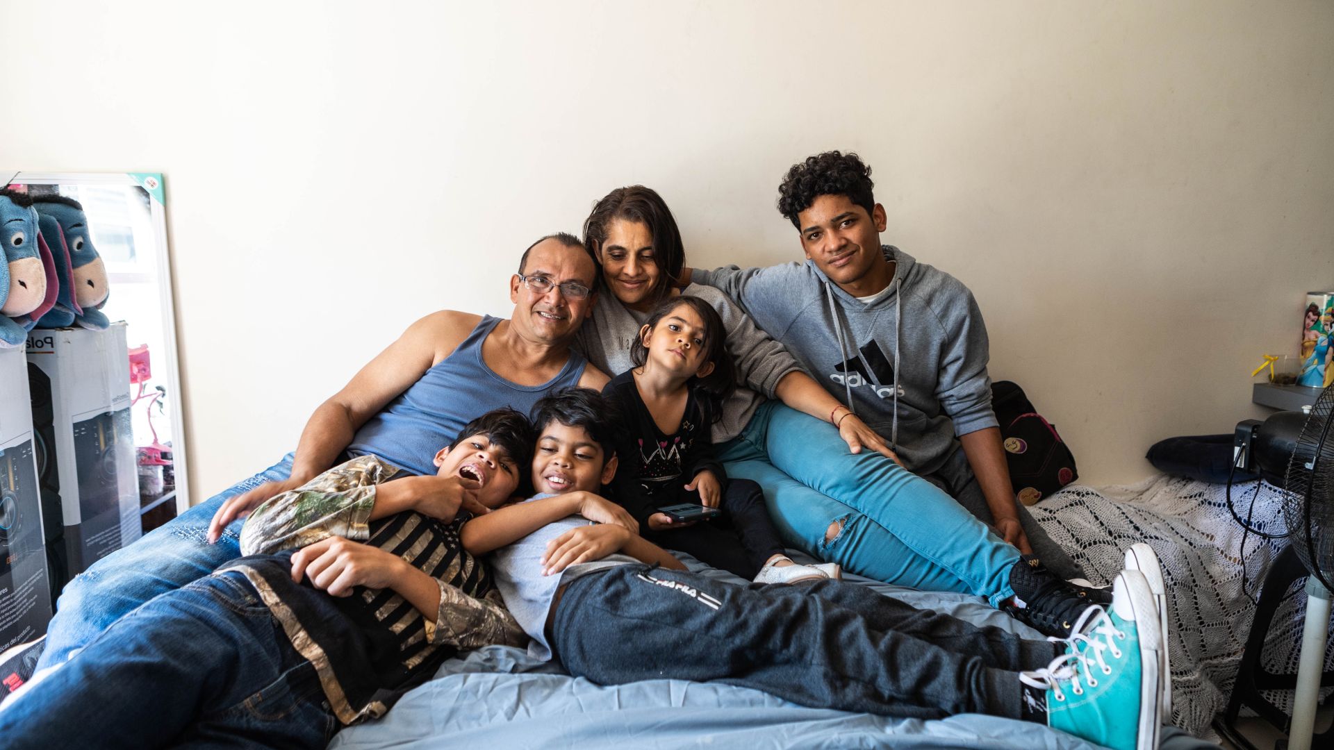 Allyson, her parents and three of her siblings pile onto a bed to take a family portrait.