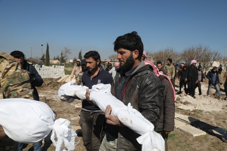 Men carrying the shrouded bodies of babies to bury