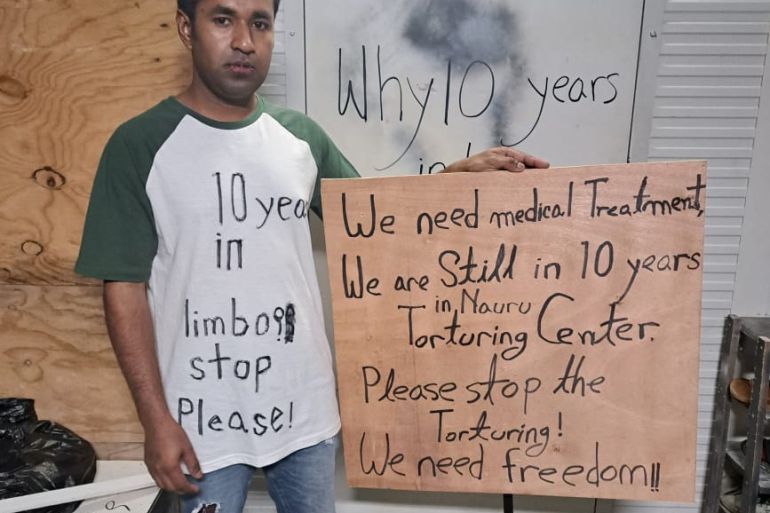 Mohammad Kaium stands with his lips sewn together, holding a placard that "We are still in 10 years in Nauru Torturing Center. Please stop the Torturing! We need freedom." Writing on his t-shirt says, "10 years in limbo stop Please!"