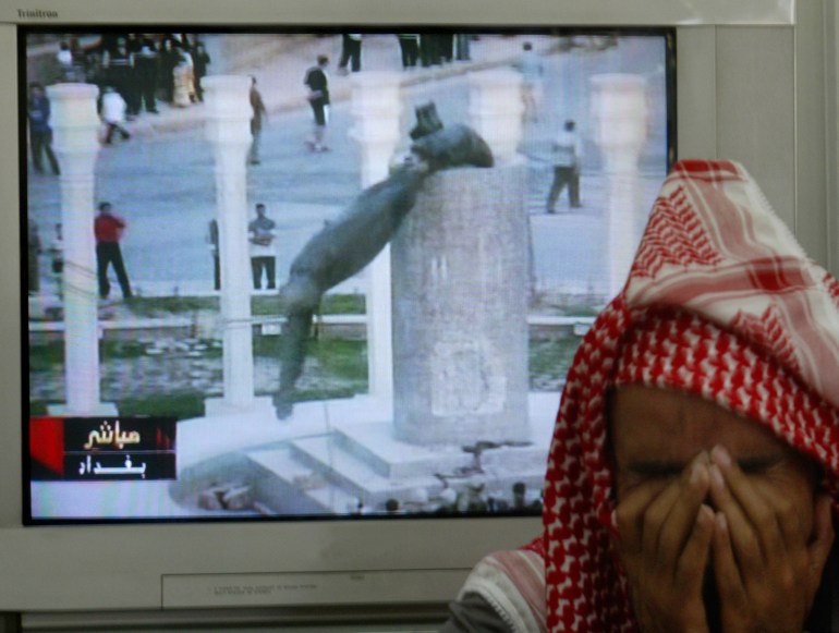 A Jordanian man in Amman covers his face as a TV shows a statue of Iraqi President Saddam Hussein falls