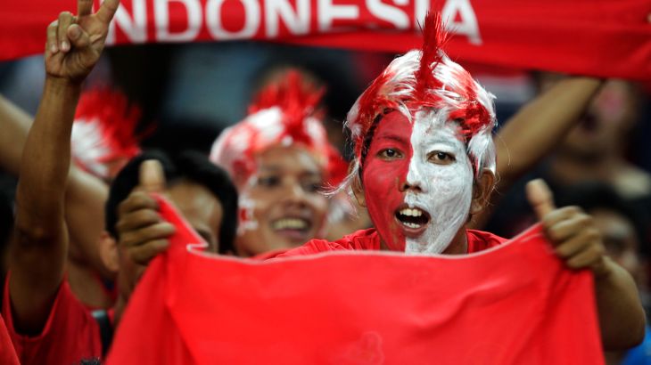 Indonesian fans dressed in national colours cheer as they hold flags and banners before the final first leg match between Indonesia and Malaysia during the ASEAN Football Federation (AFF) Suzuki Cup 2010 soccer tournament in Kuala Lumpur December 26, 2010. REUTERS/Bazuki Muhammad (KUALA LUMPUR - Tags: SPORT SOCCER)