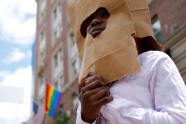 An asylum seeker from Uganda covers her face with a paper bag