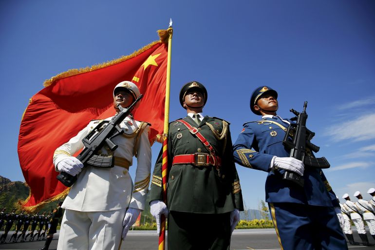 Officers and soldiers of China's People's Liberation Army hold a flag and weapons during a training session for a military parade to mark the 70th anniversary of the end of the World War Two, at a military base in Beijing, China, August 22, 2015. Troops from at least 10 countries including Russia and Kazakhstan will join an unprecedented military parade in Beijing next month to commemorate China's victory over Japan during World War Two, Chinese officials said. The parade on Sept. 3 will involve about 12,000 Chinese troops and 200 aircraft, Qi Rui, deputy director of the government office organizing the parade, told reporters in Beijing on Friday. REUTERS/Damir Sagolj